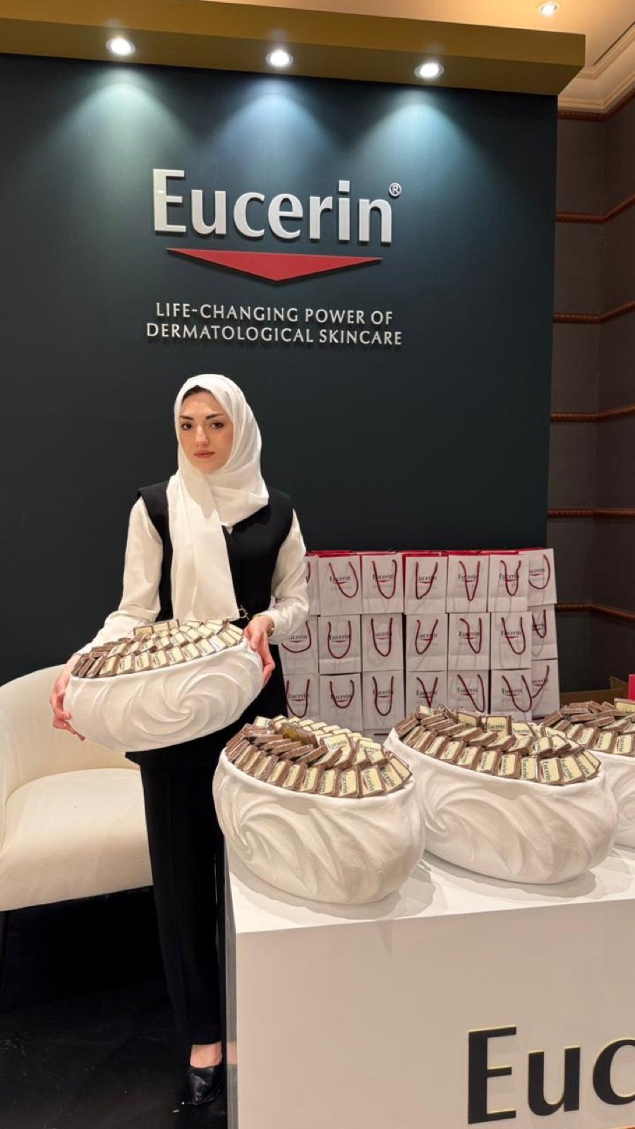 Usher presenting trays of Eucerin-branded chocolate welcome gifts
